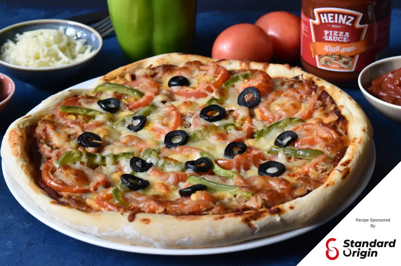 Une délicieuse pizza au thon, garnie de tomates, poivrons verts et olives noires, prête à être dégustée.