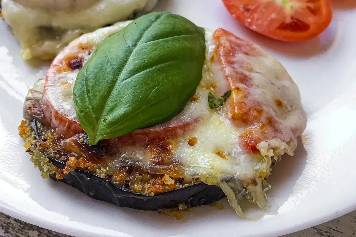Un délicieux parmigiana di melanzane, avec aubergine, tomate, fromage fondant et une feuille de basilic frais.