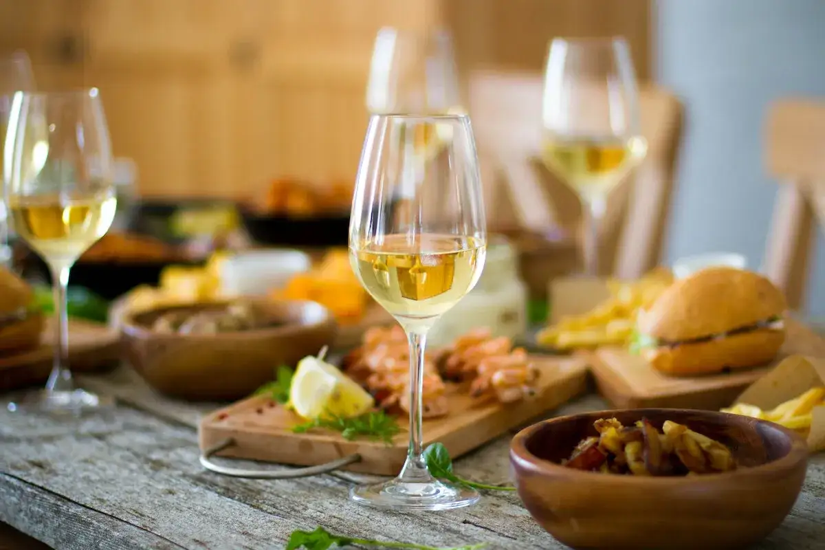 Verre de vin blanc servi avec des crevettes, un burger et des frites. Un type de vin blanc parfait pour accompagner ce repas.
