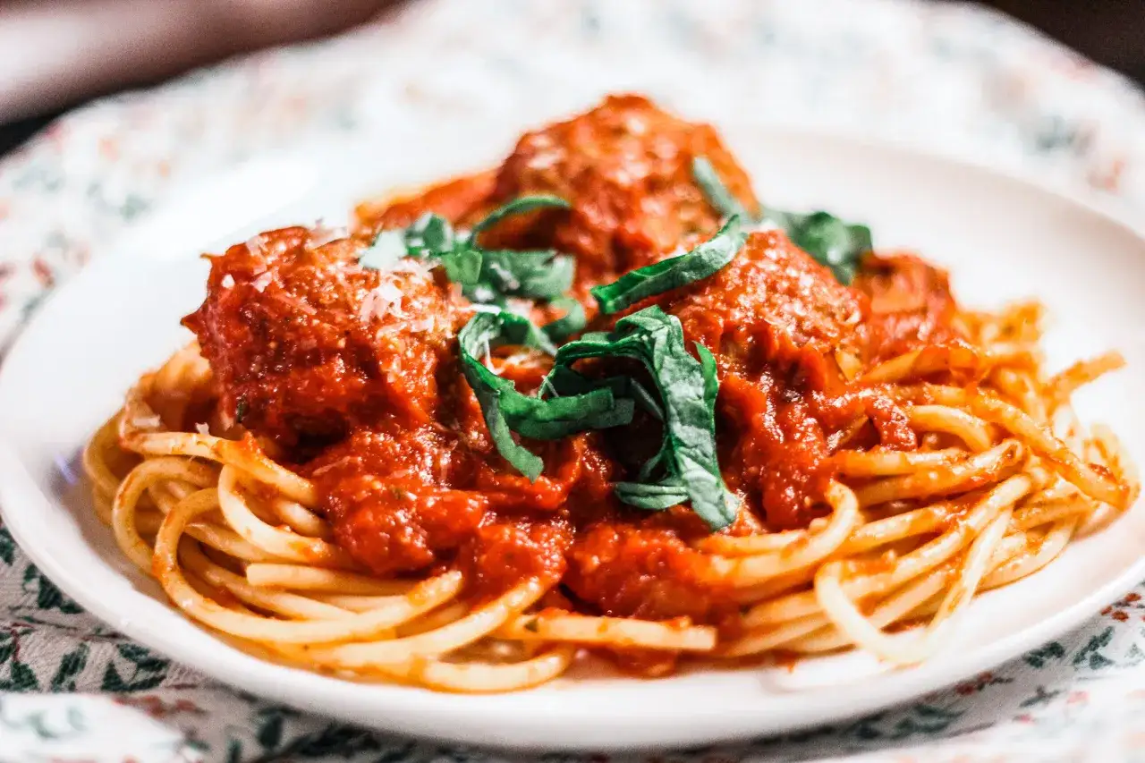 Spaghetti avec boulettes de viande italienne, sauce tomate riche et basilic frais. Un plat réconfortant, parfait pour une recette boulette de viande italienne.