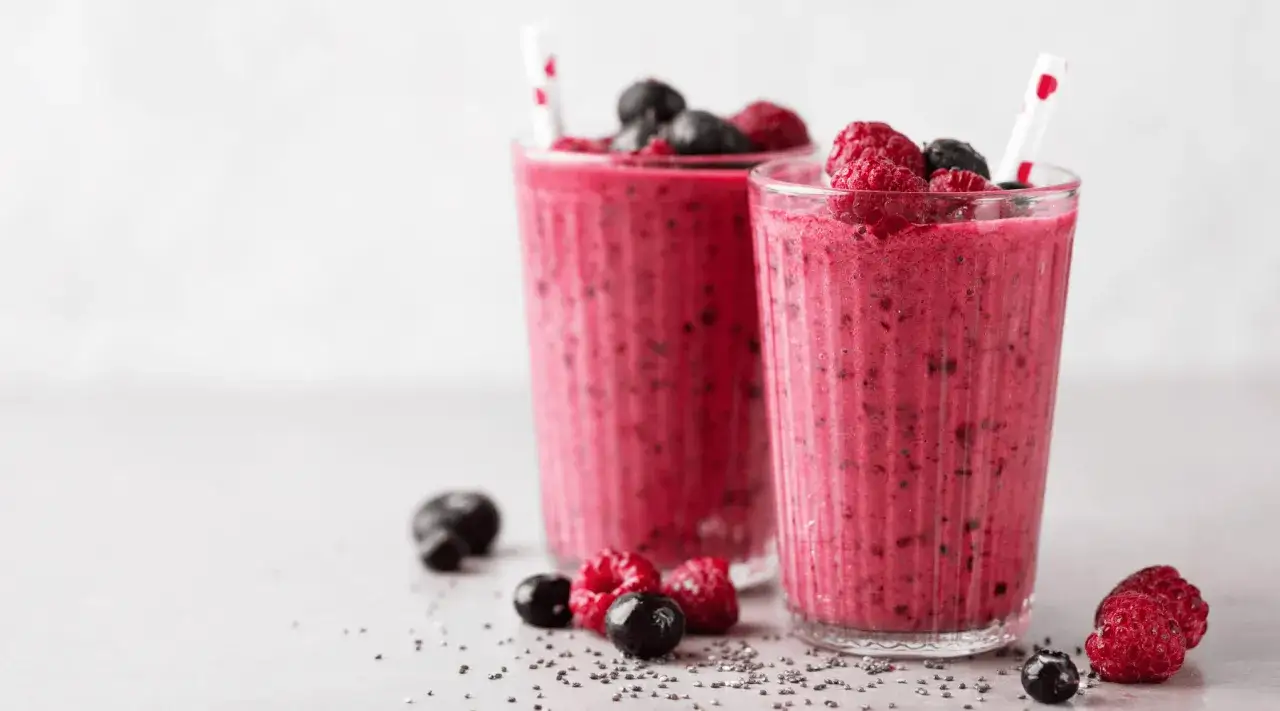 Deux verres de smoothie aux fruits rouges, garni de framboises et myrtilles. Un délice pour savoir qu'est ce qu'un smoothie !