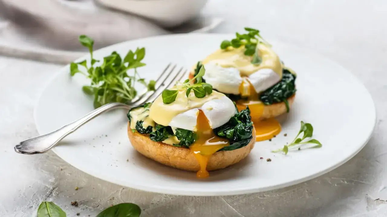 Deux œufs pochés sur un muffin anglais avec des épinards et de la sauce hollandaise, un délice d'oeuf florentine.