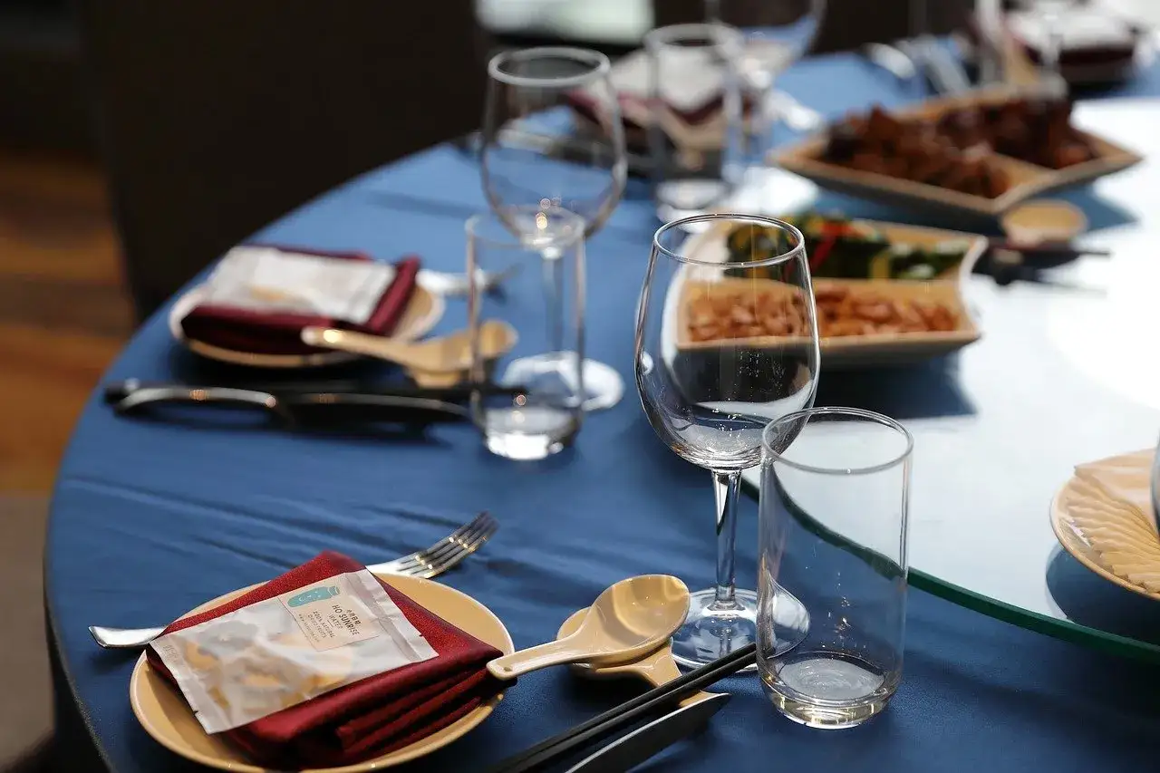 Une table dressée avec des verres, des assiettes et des couverts. Des amuse-bouches sont servis. Quel vin rouge accompagnera ce repas ?
