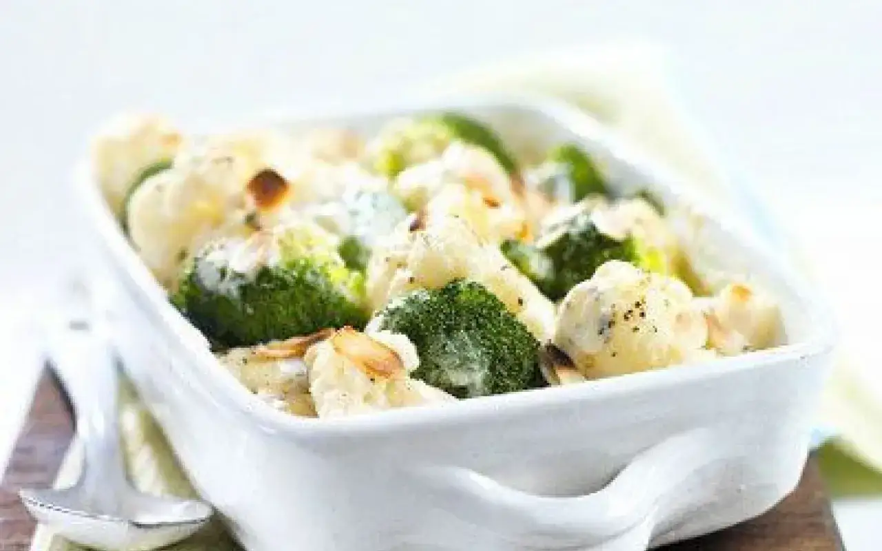 Gratin de chou-fleur et brocolis crémeux, parsemé d'amandes effilées grillées. Un délice réconfortant.