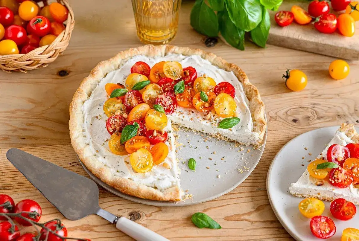 Tarte salée crémeuse garnie de tomates cerises colorées et de basilic frais. Un accompagnement tarte tomate parfait pour un repas léger.
