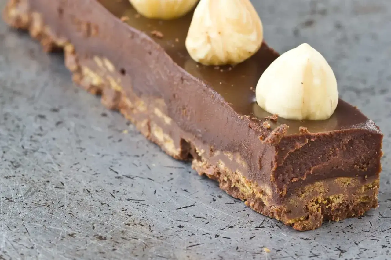 Gâteau au chocolat avec une base croustillante praliné feuilletine, garni de noisettes entières.