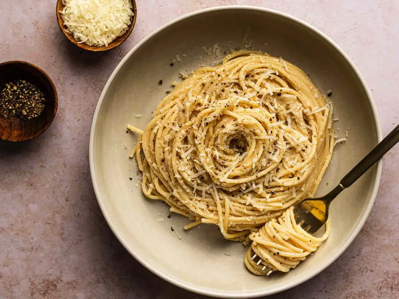 Un plat de cacio e pepe, des spaghettis crémeux saupoudrés de fromage râpé et de poivre noir fraîchement moulu, avec une fourchette enroulant une portion.