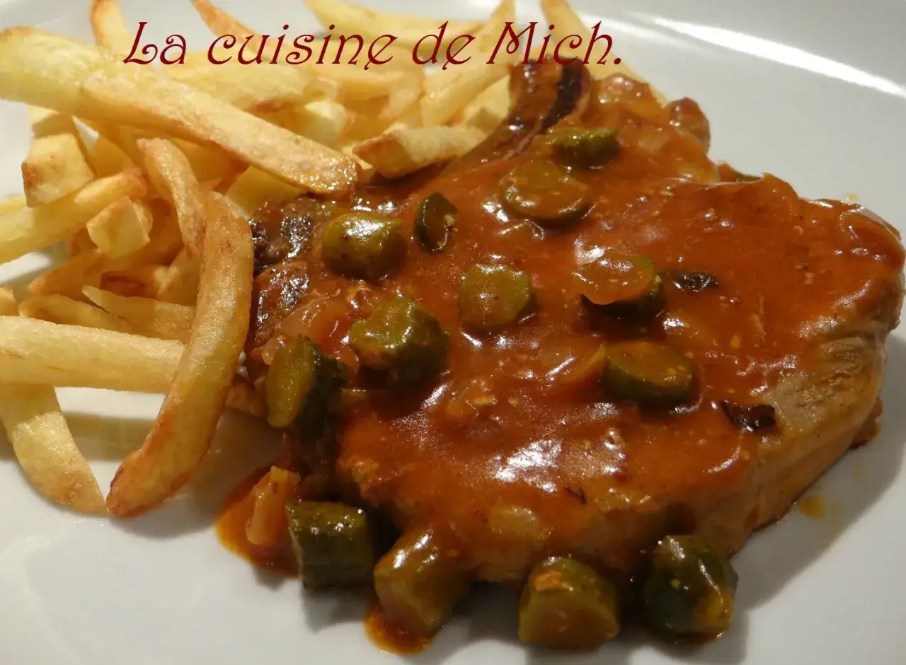 Un plat de côte de porc charcutière, généreusement nappée de sauce et accompagnée de frites dorées. Un délice de la cuisine de Mich.