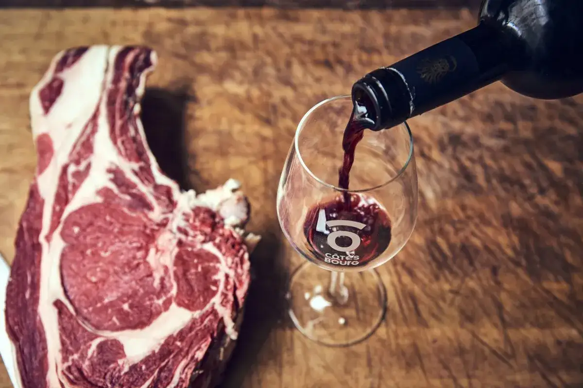 Un beau morceau de viande rouge à côté d'un verre de vin pour grillade, prêt à être dégusté.