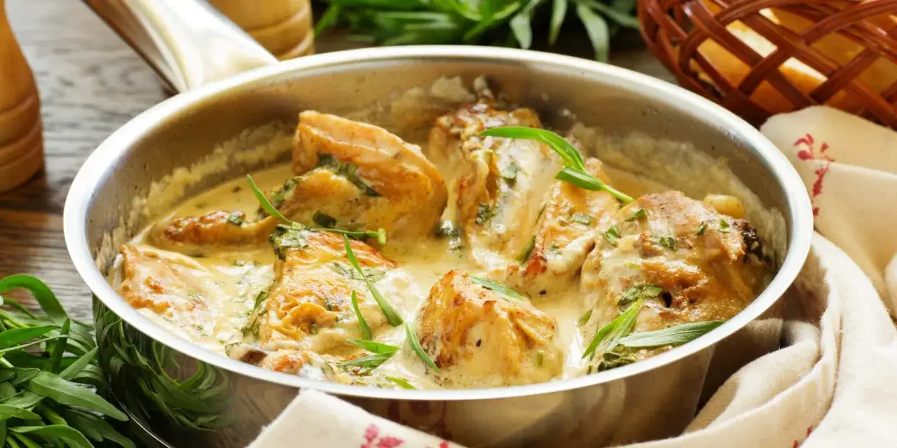 Savoureux suprême de volaille en sauce crémeuse, garni d'herbes fraîches, servi dans une poêle.