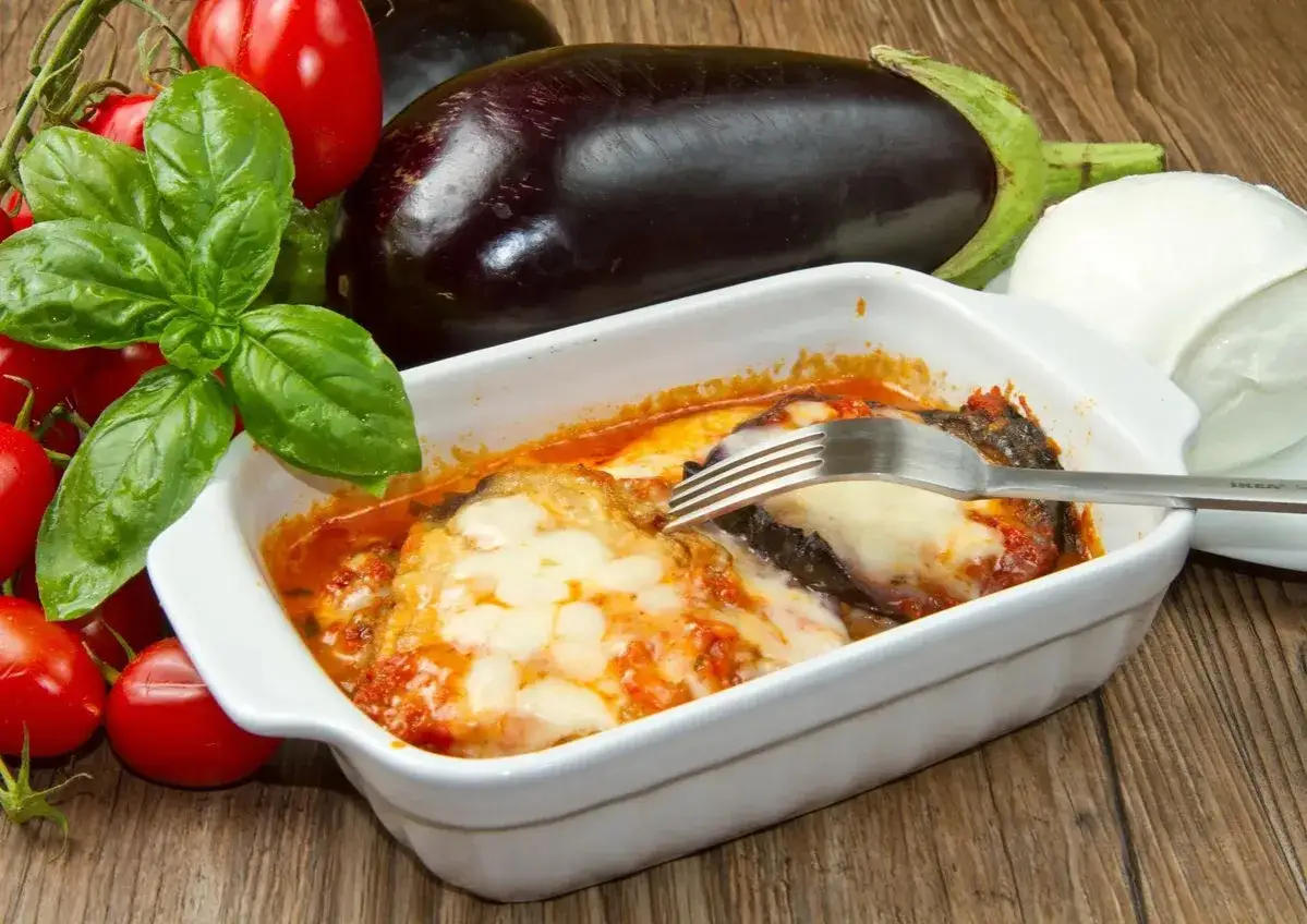Un plat d'aubergine mozzarella gratinée, avec des tomates fraîches et du basilic.