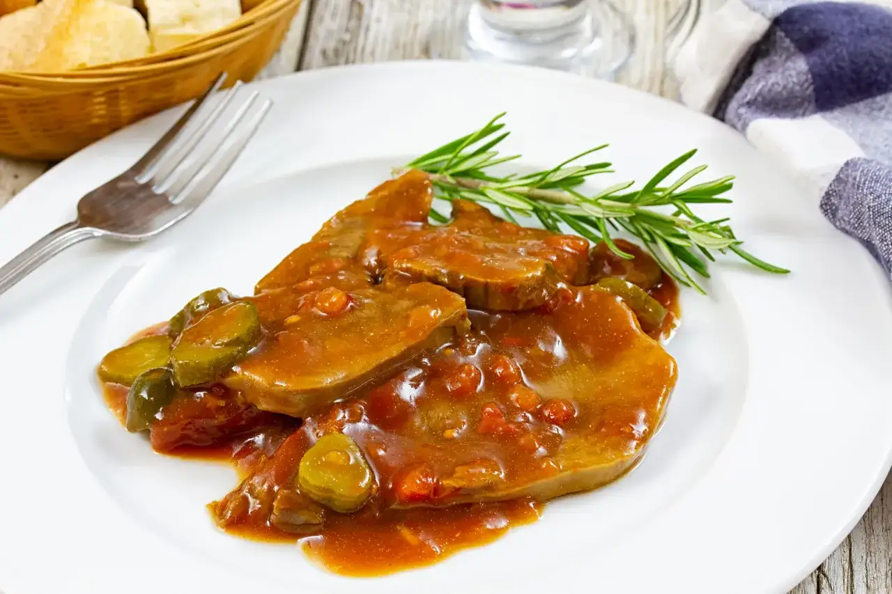 Tranches de langue de bœuf nappées d'une sauce piquante aux cornichons et garnies de romarin.