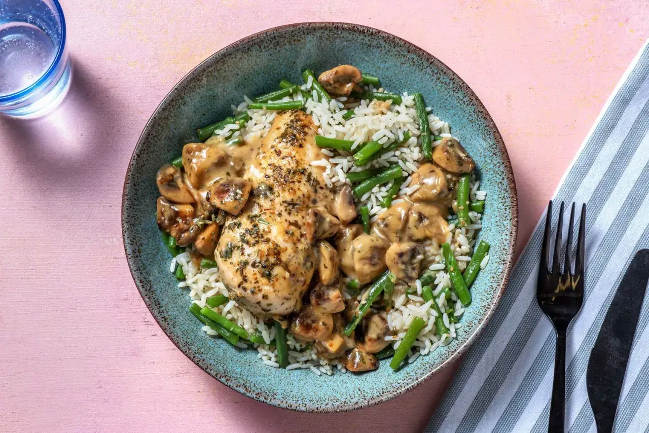 Délicieuse escalope de poulet crémeuse aux champignons, servie sur un lit de riz et haricots verts. Un plat savoureux et réconfortant.