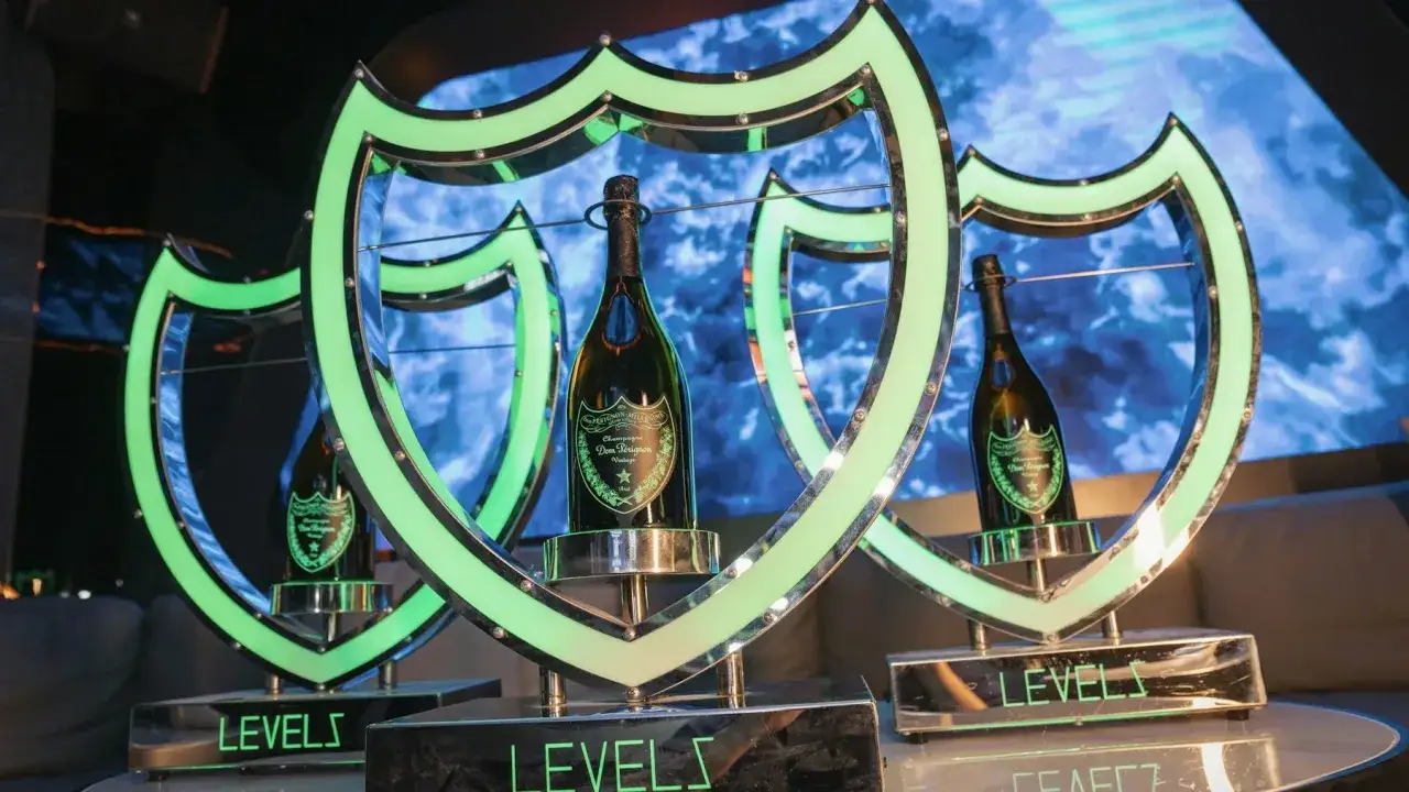 Trois bouteilles de champagne Dom Pérignon, présentées dans des cadres lumineux en forme de blason vert. Le champagne est-il un vin ? Oui, et celui-ci est de luxe.