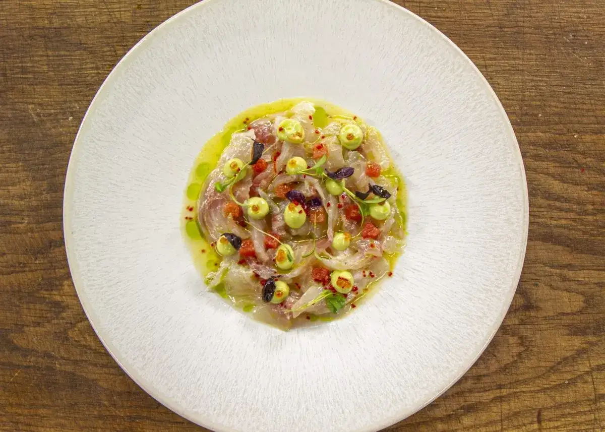 Un délicieux ceviche de daurade, frais et coloré, garni de perles vertes, de dés de tomates et de fines herbes, baignant dans une sauce légère.
