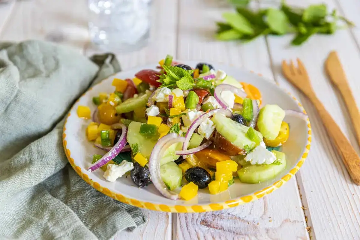 Une assiette color&eacute;e de salade &agrave; la grecque, garnie de feta, olives, concombres, tomates et poivrons, pr&ecirc;te &agrave; &ecirc;tre d&eacute;gust&eacute;e.