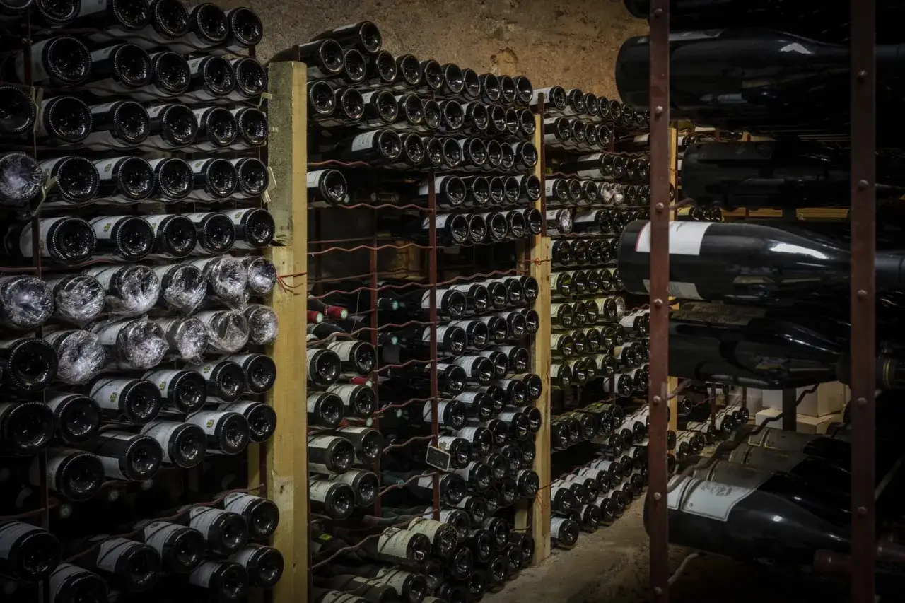 Cave à vin sombre remplie de bouteilles, certaines emballées. La conservation du beaujolais nouveau est assurée dans ce lieu frais.