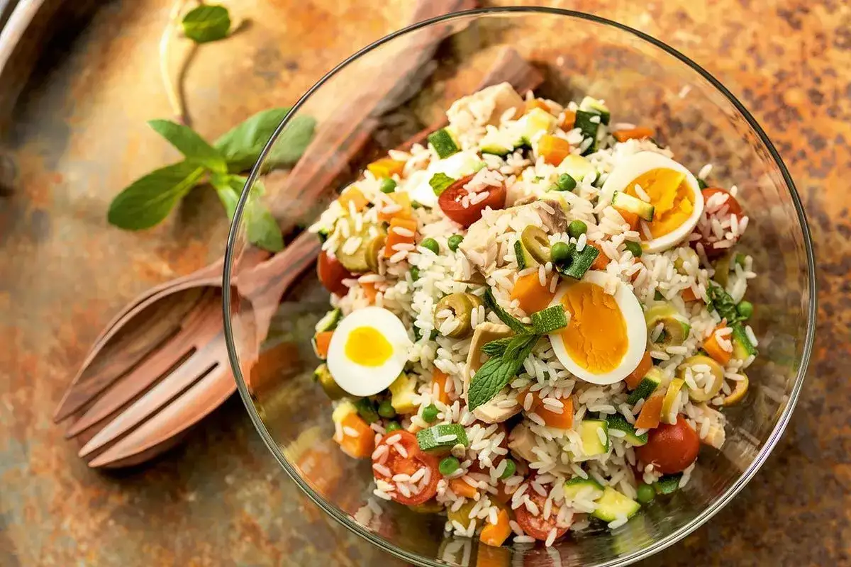 Salade de riz thon colorée avec œufs durs, tomates, olives et légumes croquants. Un plat frais et complet.