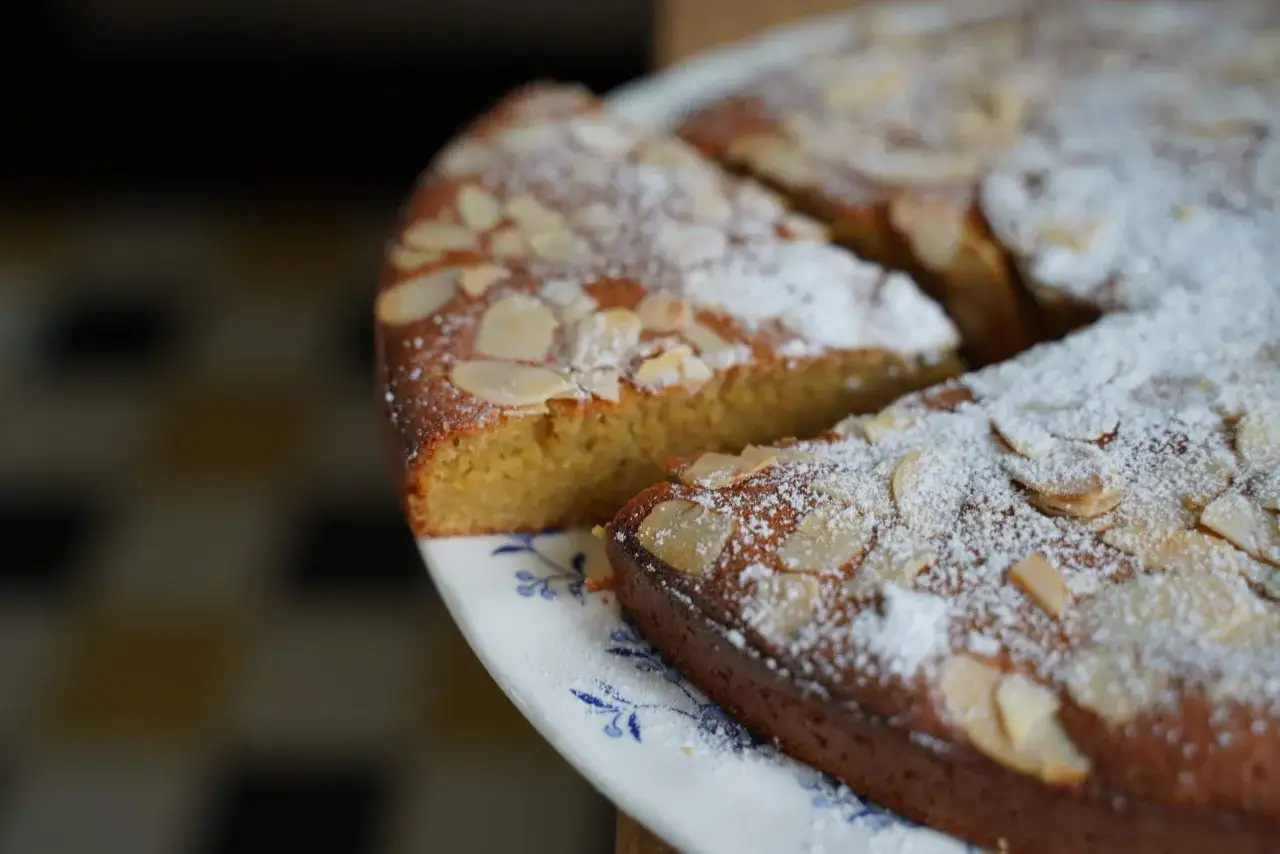 Un d&eacute;licieux g&acirc;teau arabe au miel, saupoudr&eacute; de sucre glace et d'amandes effil&eacute;es, sur une assiette orn&eacute;e de motifs bleus.