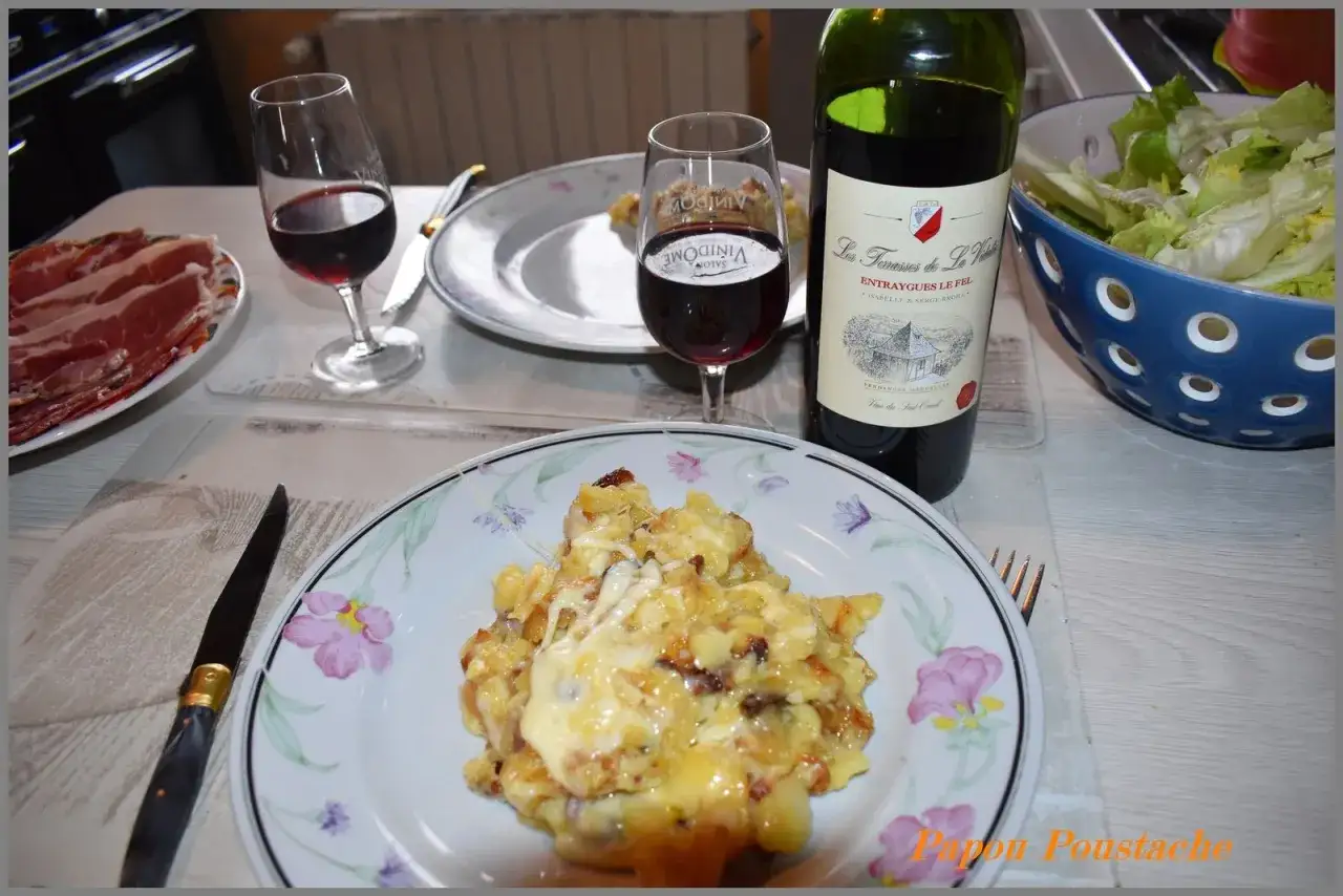 Un repas convivial avec un vin rouge et une g&eacute;n&eacute;reuse truffade, accompagn&eacute; de charcuterie et d'une salade verte.
