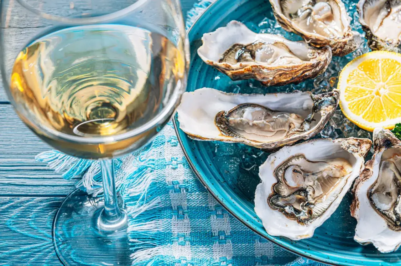 Un verre de vin blanc frais et des huîtres sur glace, un accord parfait pour savoir quel vin avec les huîtres.