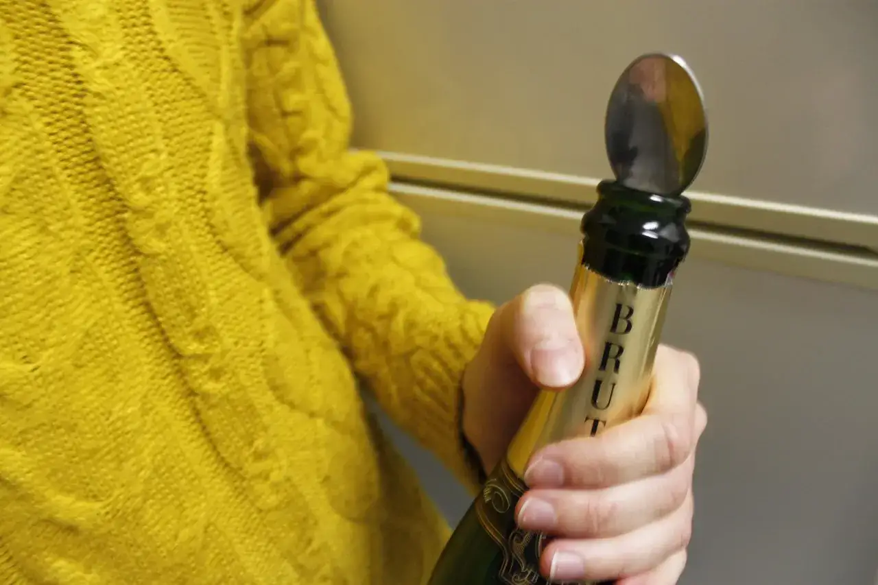 Une cuillère est insérée dans le goulot d'une bouteille de champagne pour montrer comment refermer une bouteille de champagne.