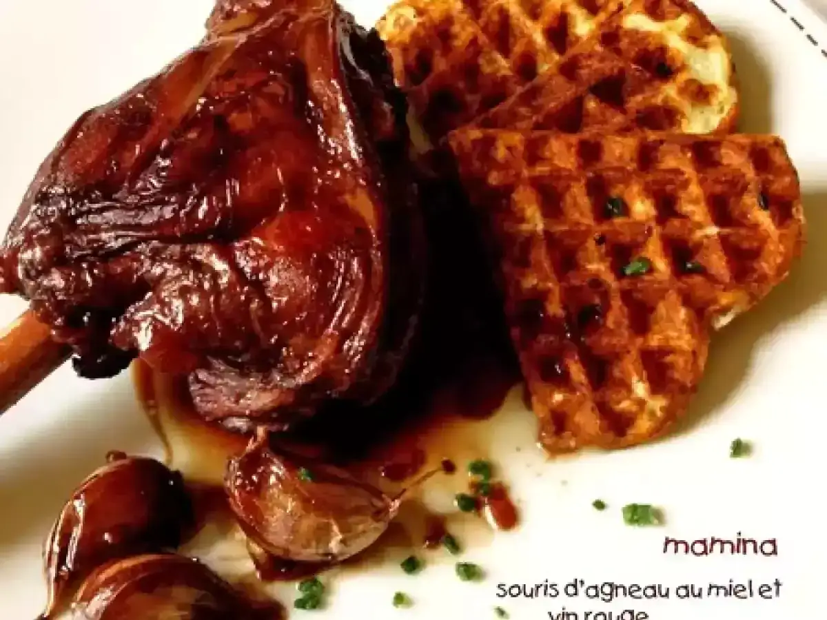 Souris d'agneau au miel et vin rouge, servie avec des gaufres croustillantes et des oignons caramélisés. Un plat savoureux et réconfortant.
