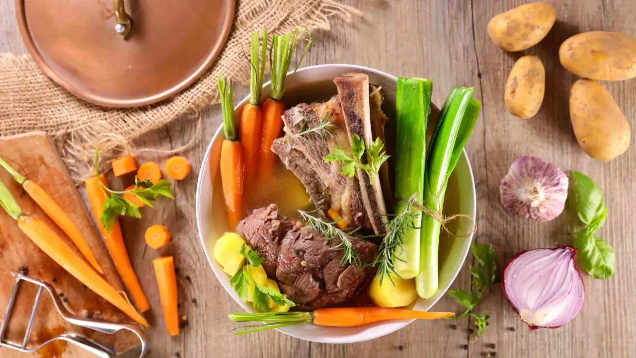 Un plat de pot-au-feu cocotte minute avec viande, carottes, poireaux et pommes de terre.