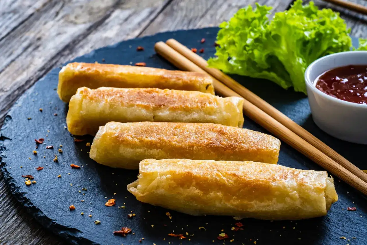 Nems au poulet dor&eacute;s et croustillants, servis avec une sauce rouge et une salade verte. Parfait pour une recette facile.