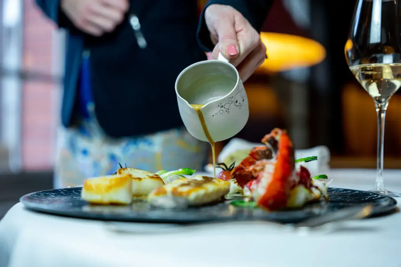 Un plat de Saint-Jacques poêlées et homard, arrosé d'une sauce. Parfait pour savoir que manger avec du Sauternes.