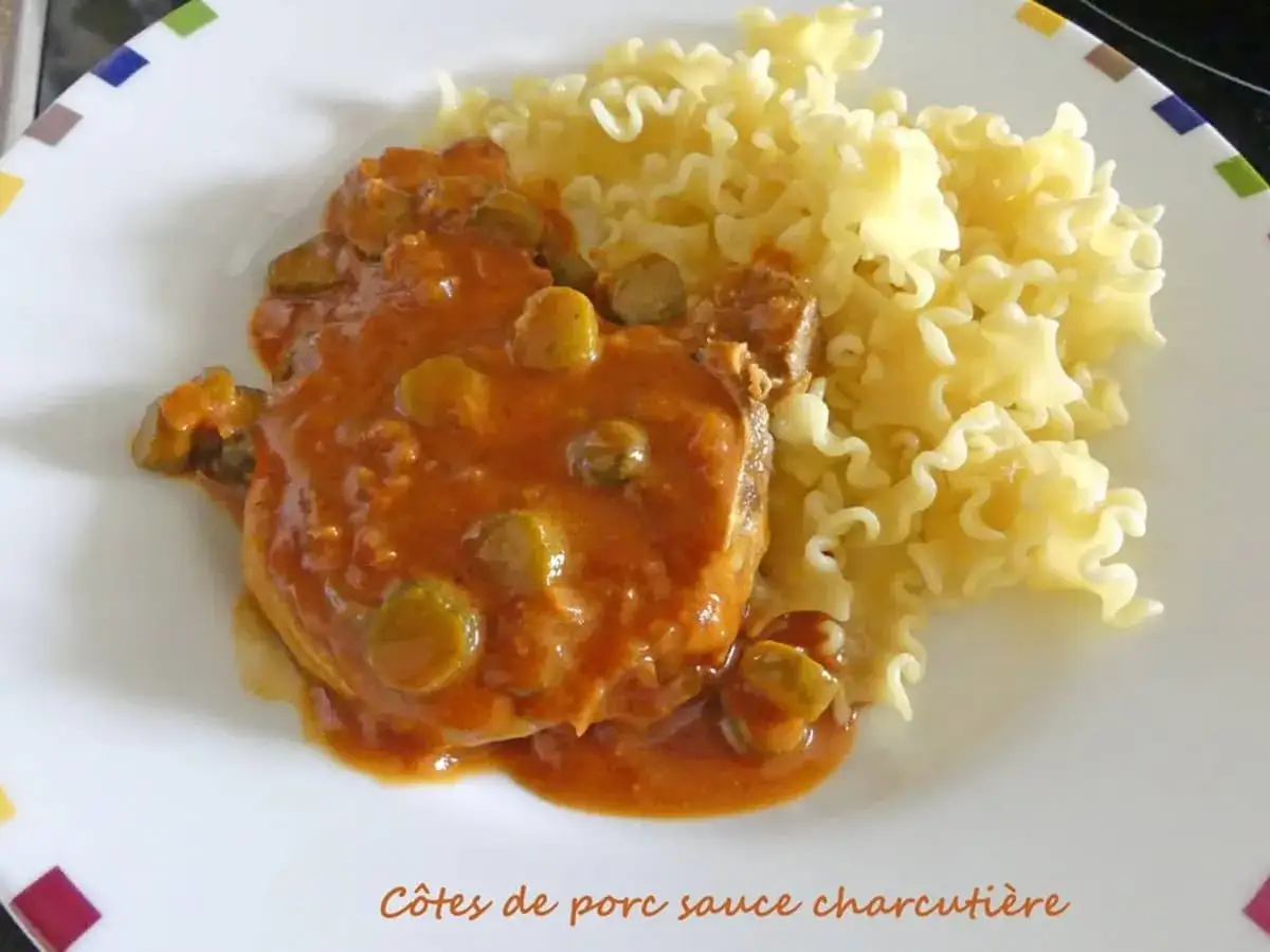 Côtes de porc sauce charcutière savoureuses, nappées d'une sauce onctueuse aux cornichons, accompagnées de pâtes frisées. Un délice !