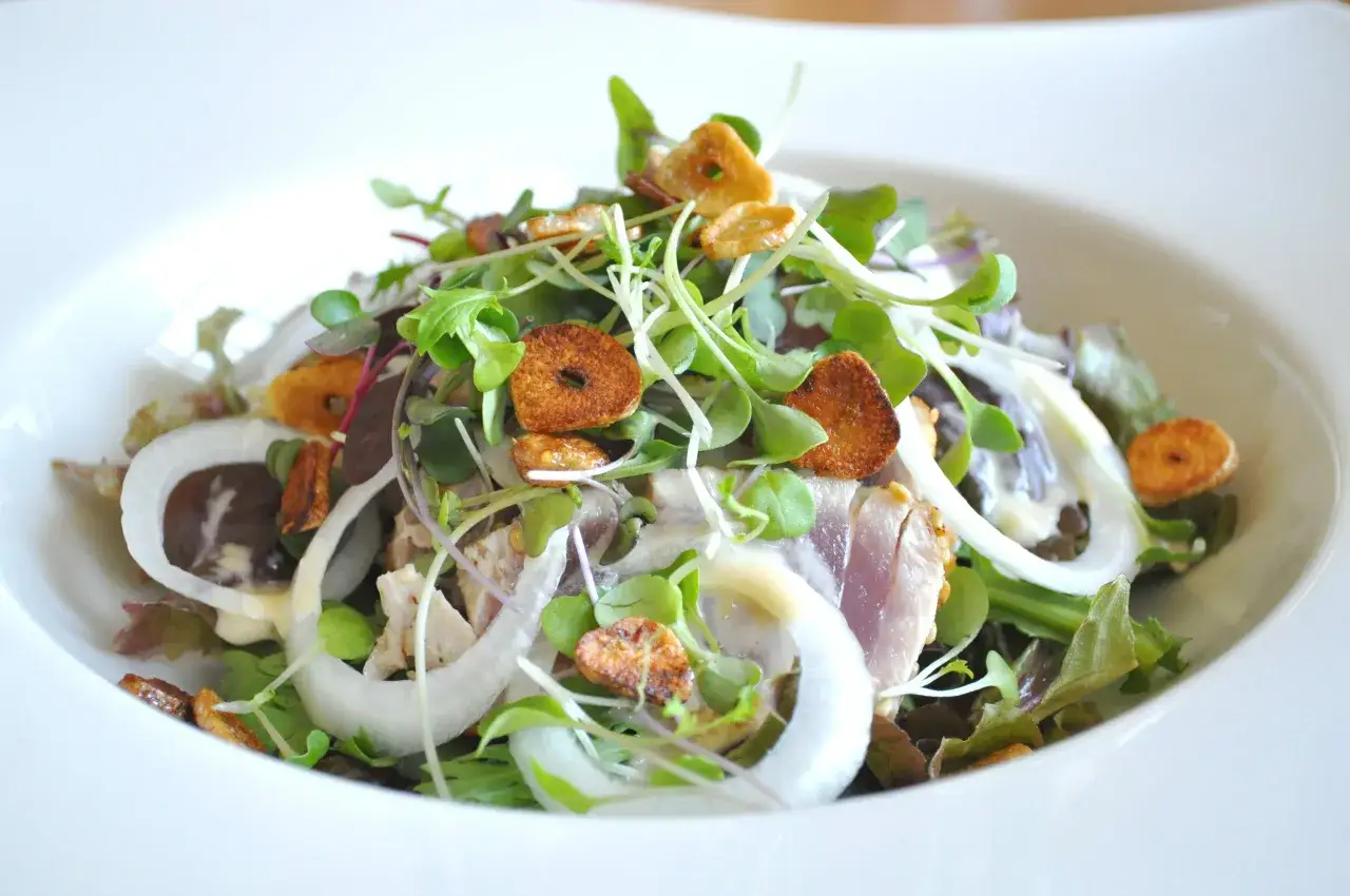 Salade fraîche avec tataki de thon, oignons croquants et jeunes pousses, un accompagnement léger et savoureux.
