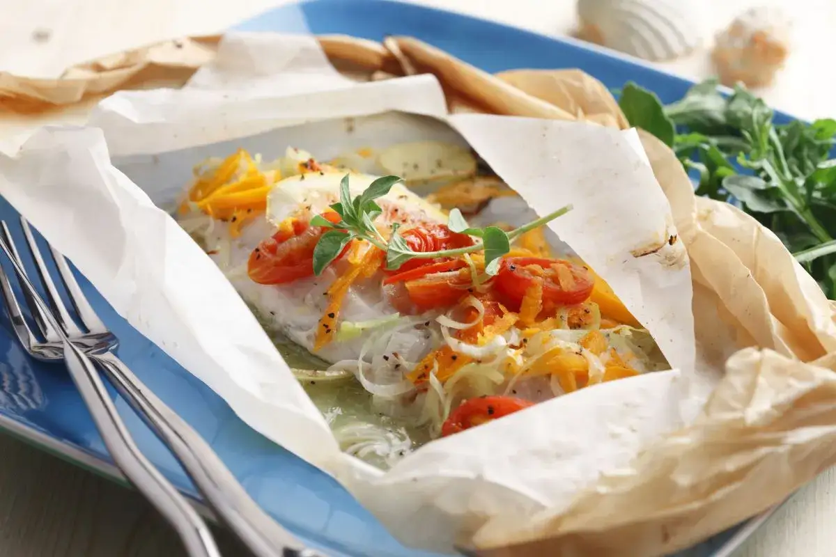 Un plat de cabillaud en papillote, garni de tomates cerises et d'herbes. Un délice qui invite à se demander quel vin avec du cabillaud.