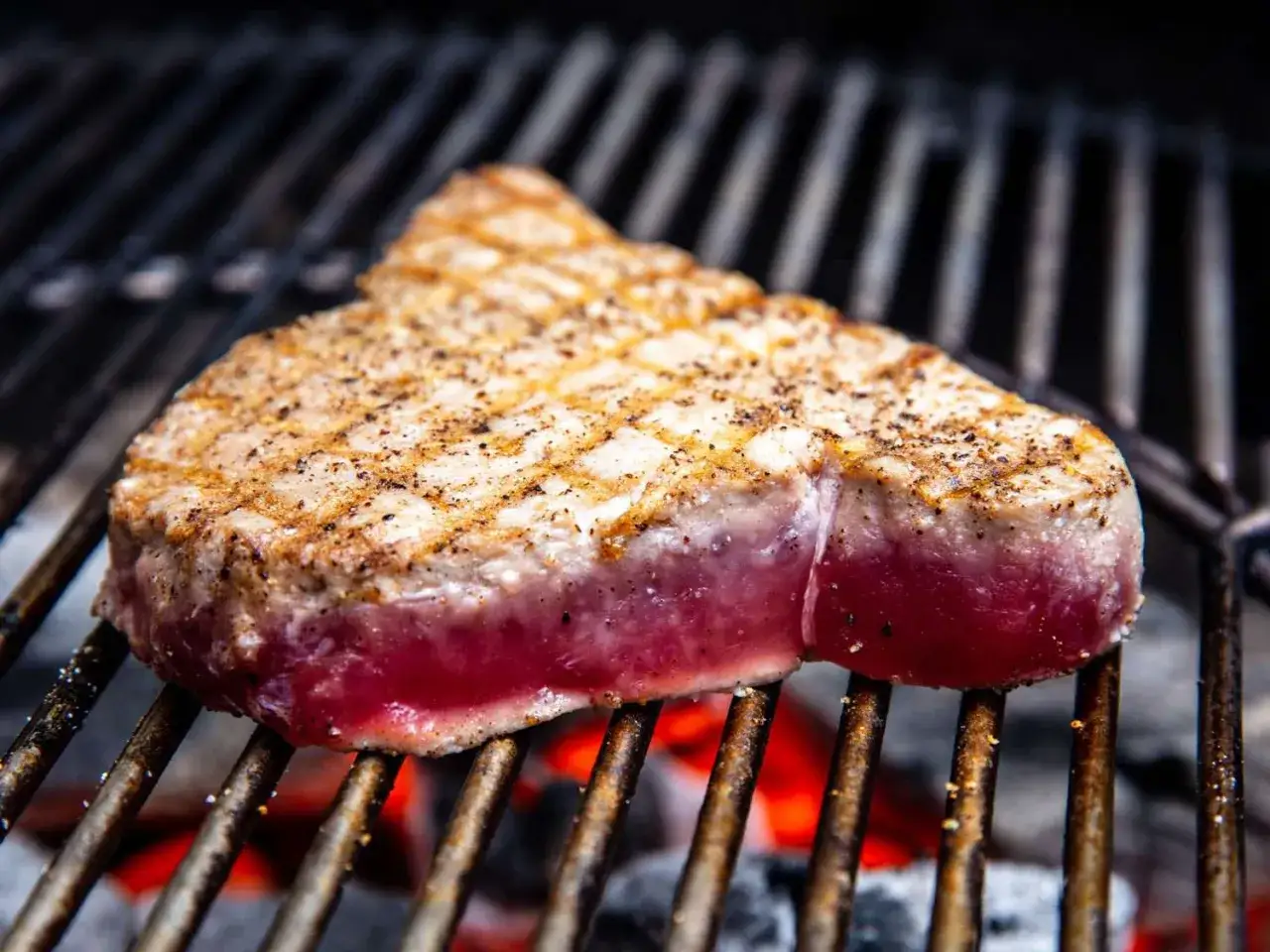 Un beau morceau de thon au barbecue, grillé à la perfection, avec des marques de grill distinctes et une belle couleur rosée à l'intérieur.