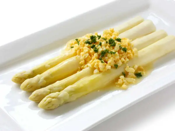 Asperges à la flamande : des asperges blanches tendres nappées d'une sauce savoureuse et garnies d'œufs brouillés et de persil frais.